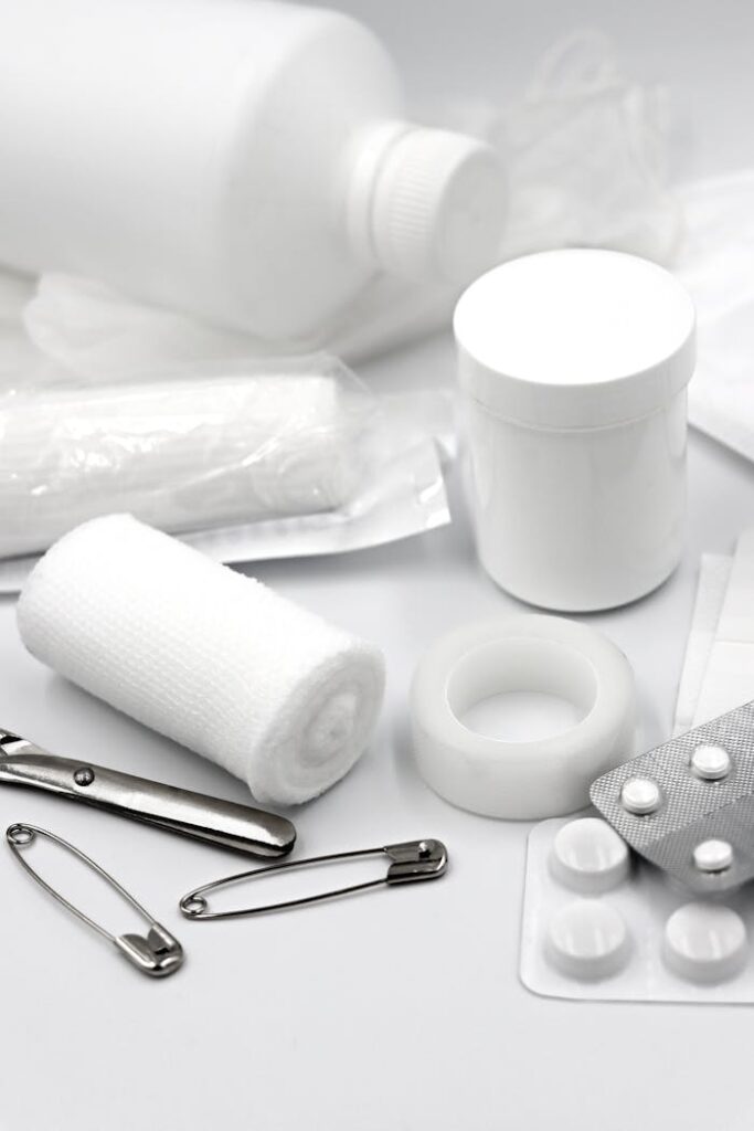A detailed arrangement of essential first aid supplies including bandages, safety pins, and medication.